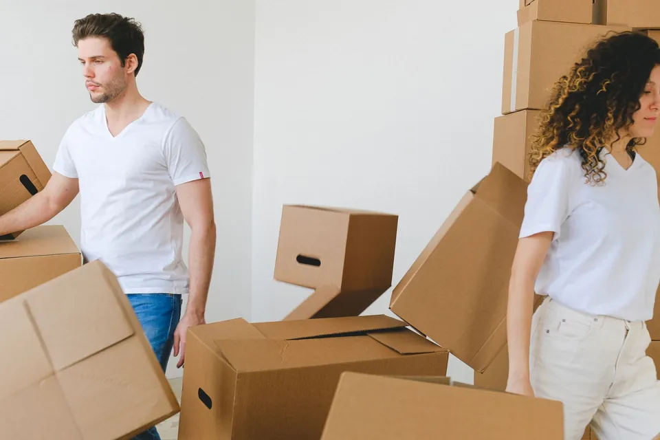 Paar packt Umzugskartons in der neuen Wohnung aus