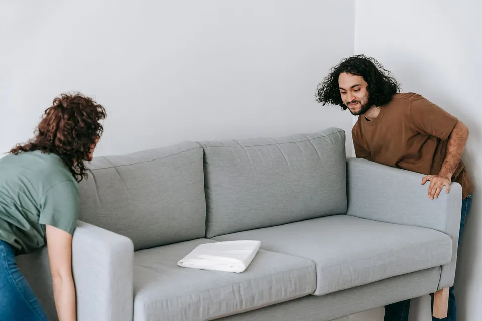 Helfer tragen ein Sofa aus der Wohnung zum Transporter